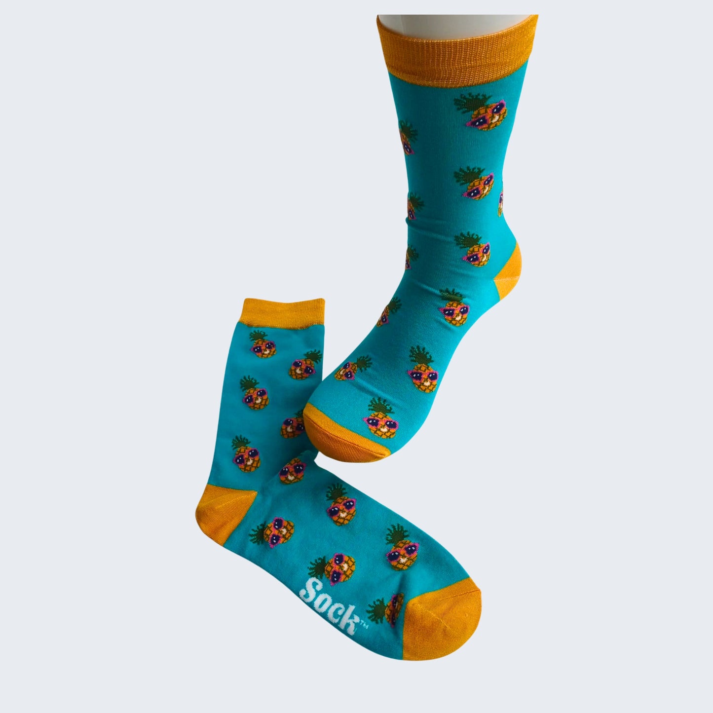 Teal bamboo socks with pineapple design, yellow cuff and toe, displayed on mannequin foot against white background.