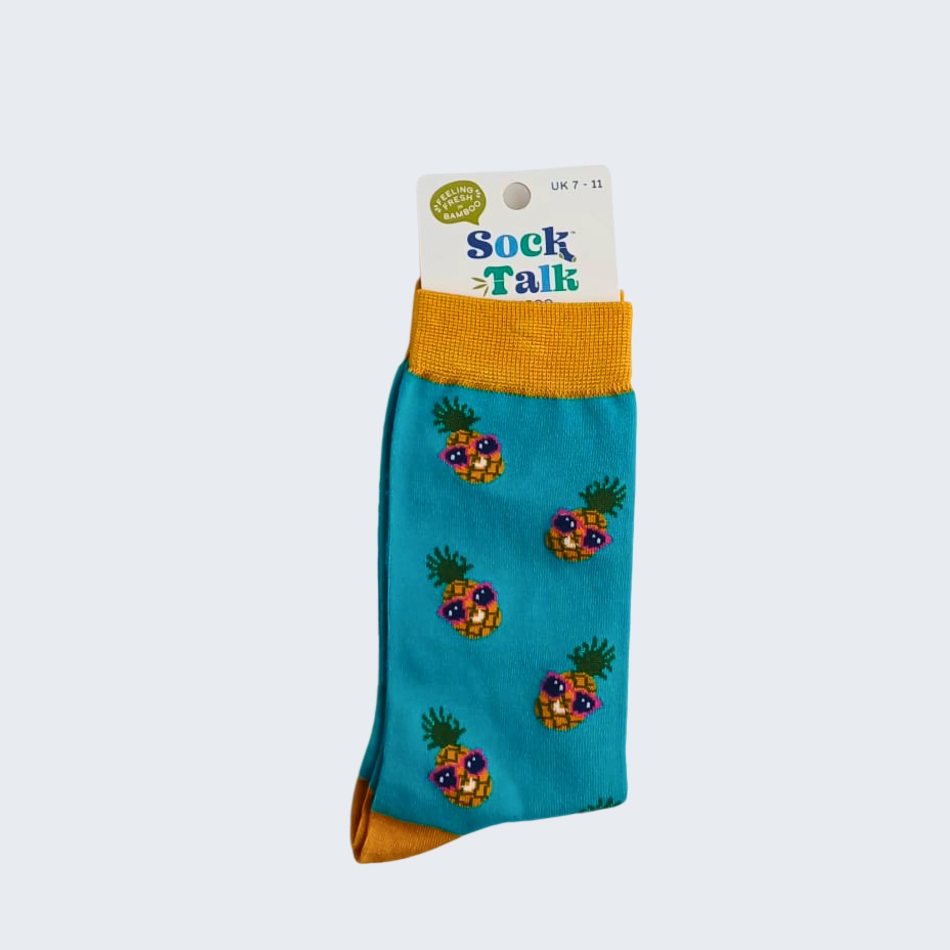Teal bamboo socks with pineapple print, shown in retail packaging with label, on white background.