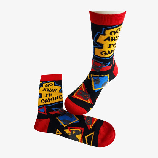 Pair of novelty bamboo socks with “Go Away I’m Gaming” slogan, shown flat and on mannequin foot, with bold red, yellow and blue graphics.