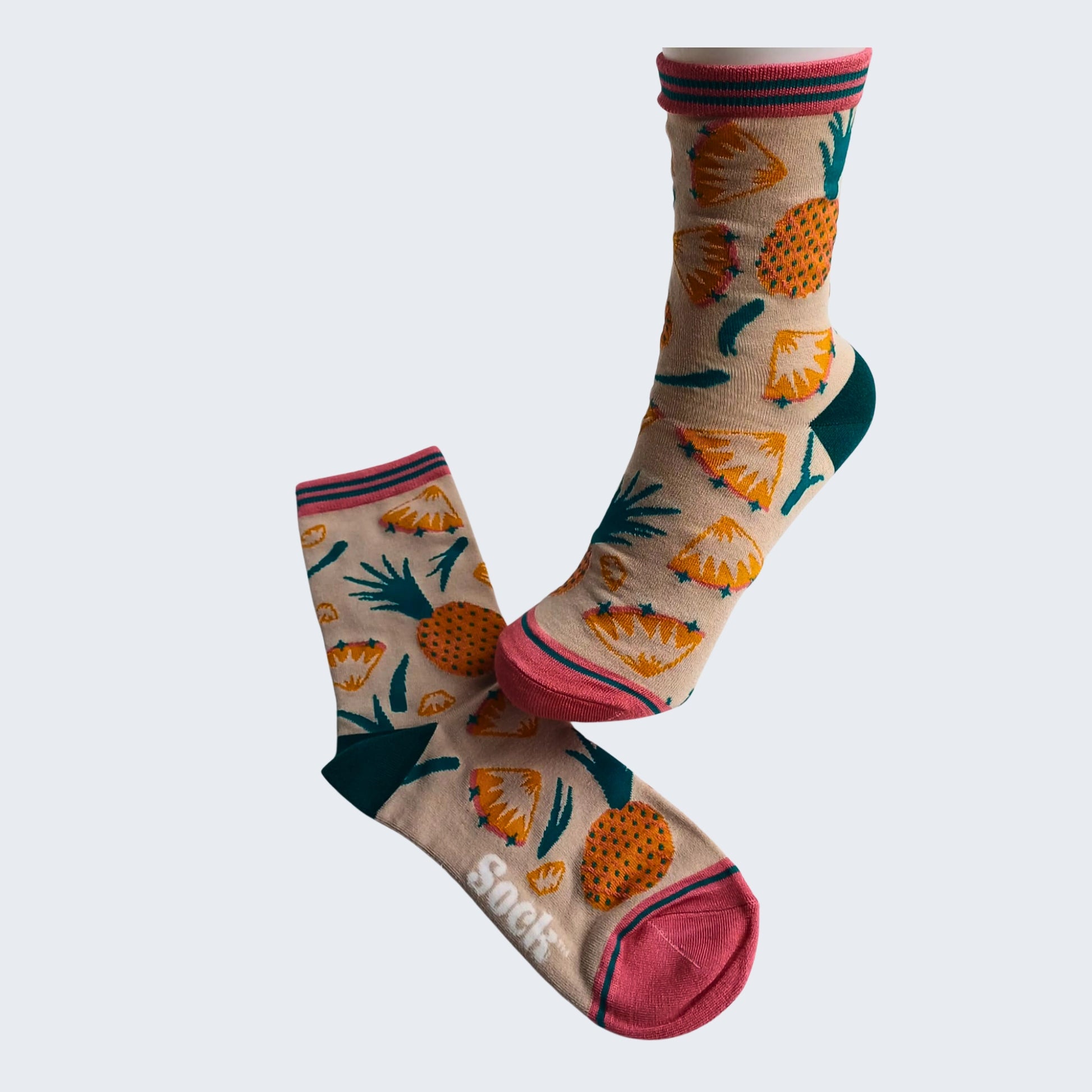 Beige bamboo socks with colourful pineapple design, pink cuff and toe, shown on mannequin foot against white background.