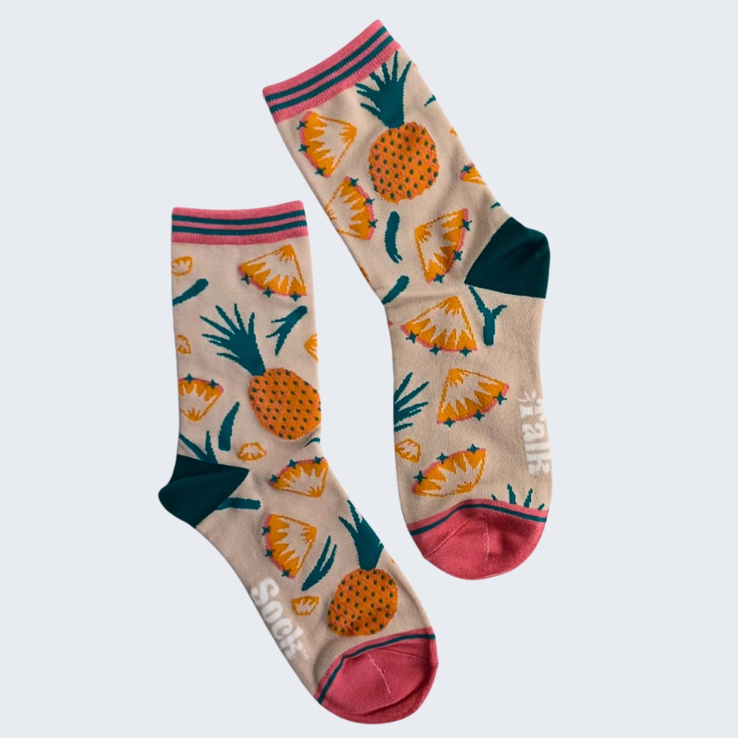 Pair of beige bamboo socks with pineapple print, pink cuffs and toes, flat lay on white background.