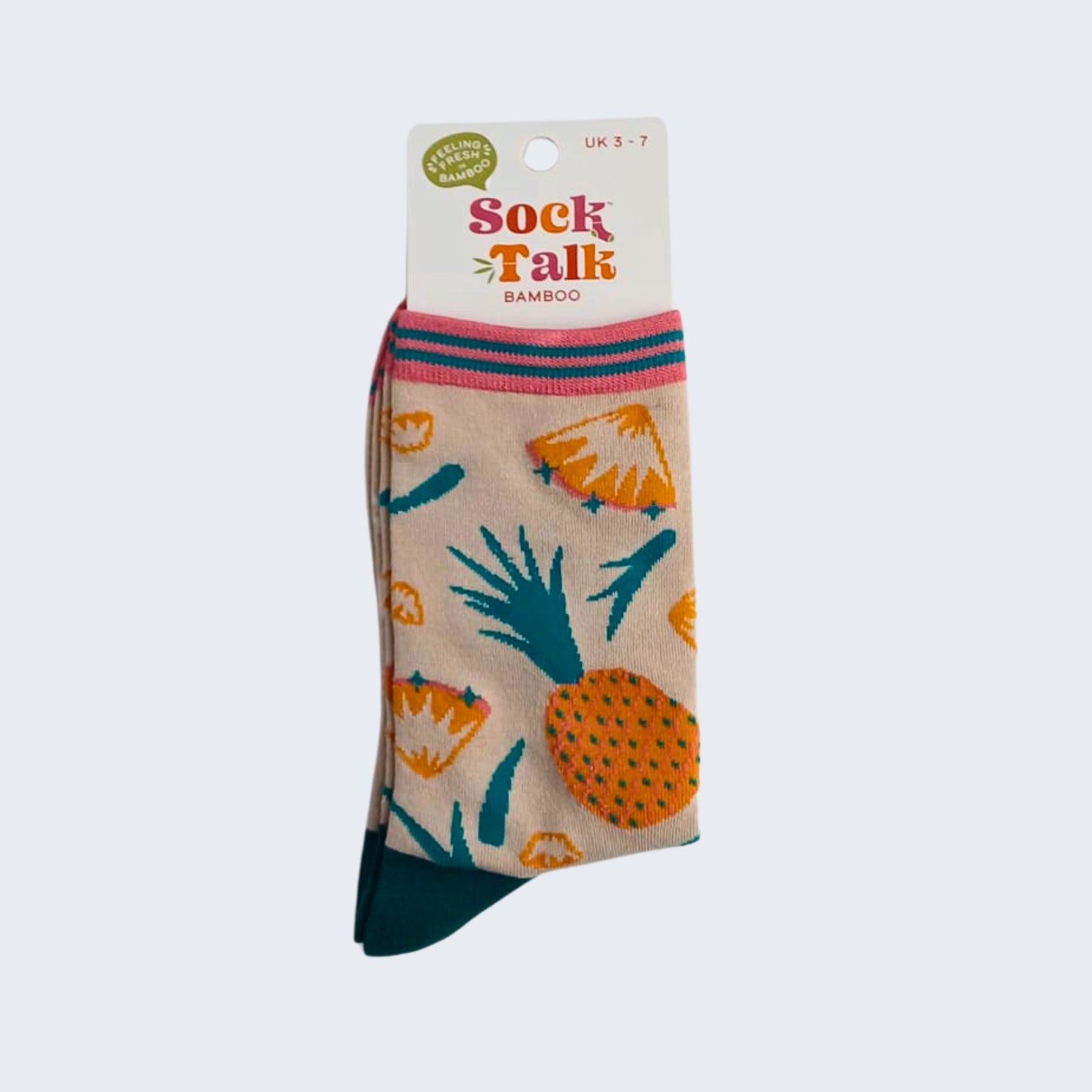 Beige bamboo socks with pineapple print shown in packaging with label, displayed on white background.
