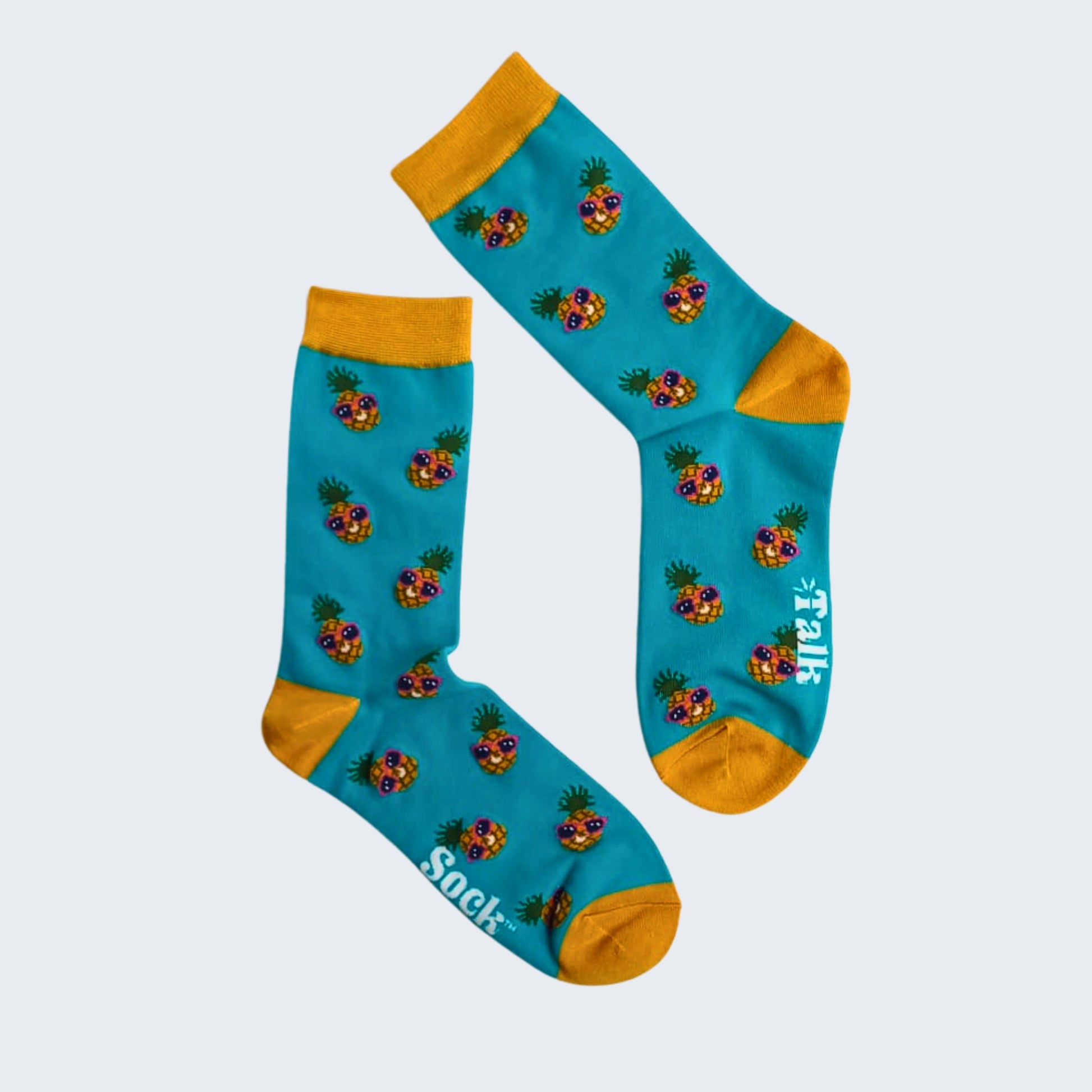 Pair of teal bamboo socks with pineapple print and yellow cuffs and toes, flat lay on white background.